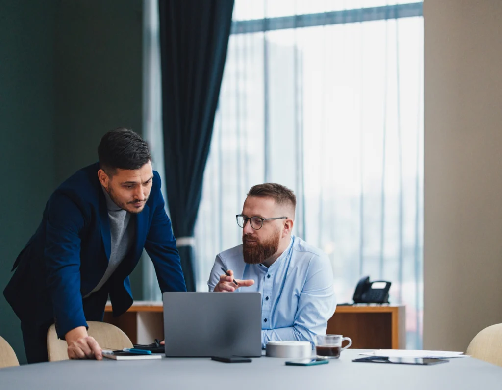 Procurement and Finance officers discussing how RightSpend can help their business, looking at the RightSpend system on a laptop