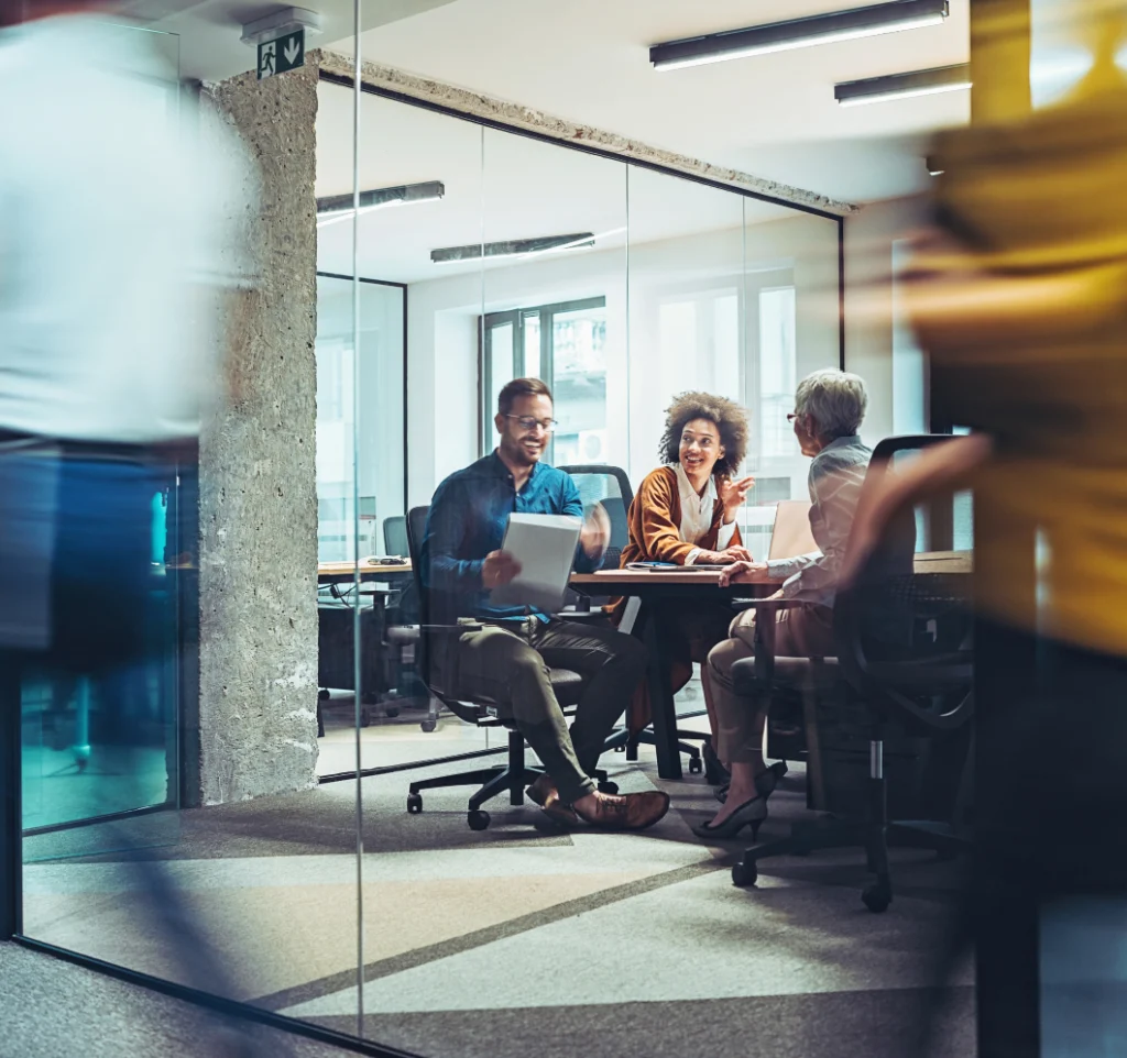 Marketing and Procurement collaborating in a meeting with blurred people walking past