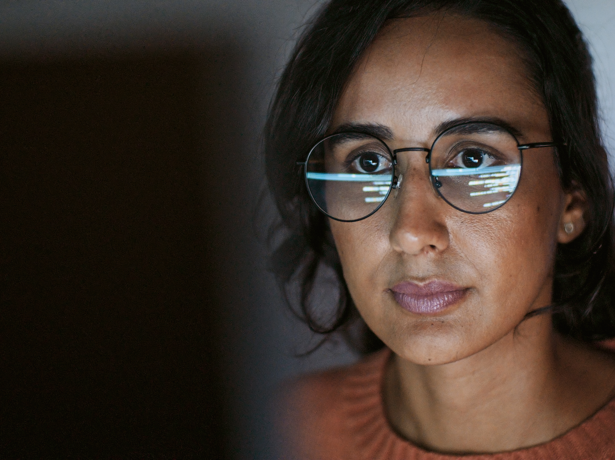 Marketing Procurement individual looking a screen to benchmark their agency fees, with data reflected in her glasses